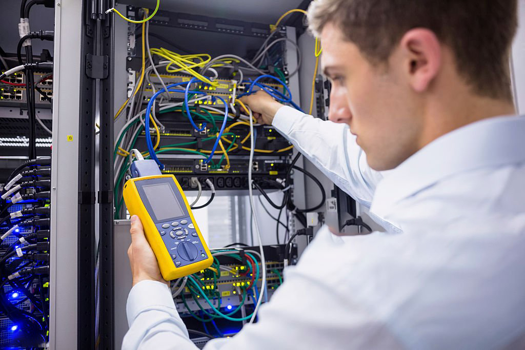 Serious technician using digital cable analyzer on server in large data center