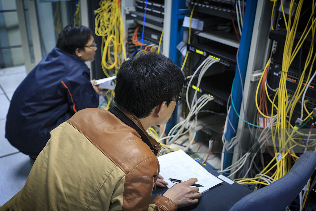Two network administrators are working in the server room