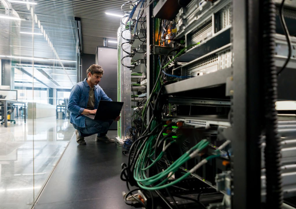 Latin American computer technician fixing a network server the office - focus on foreground