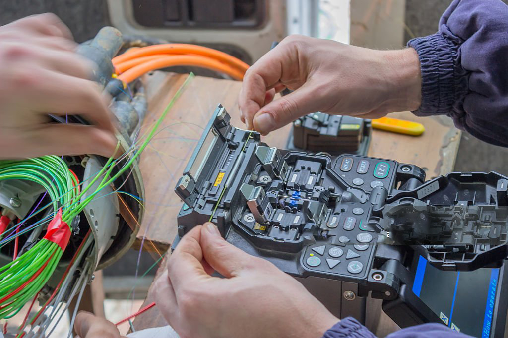 Fibre optic technician splicing fibers. Splicing two fibers using the fusion splicer.