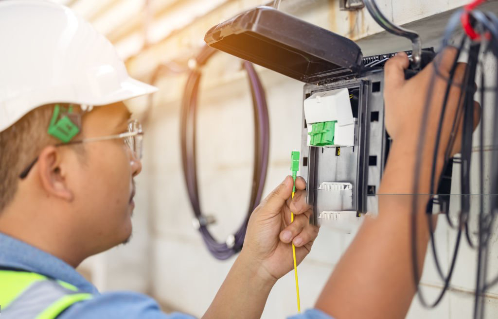 An internet technician is repairing or maintaining a fiber optic connection by opening a fiber optic connector.